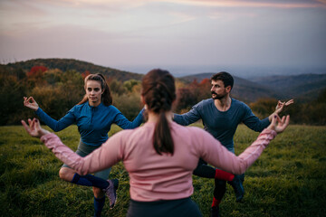 Group of friends spending a late afternoon, practicing yoga. Shot of a group of people practicing...