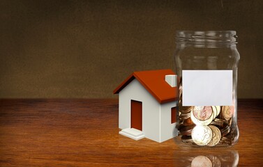Family budget concept. Big jar with coins and toy house