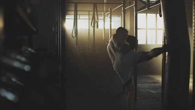 In a large boxing class young attractive guy with perfect muscle boxing hard in a punching bag
