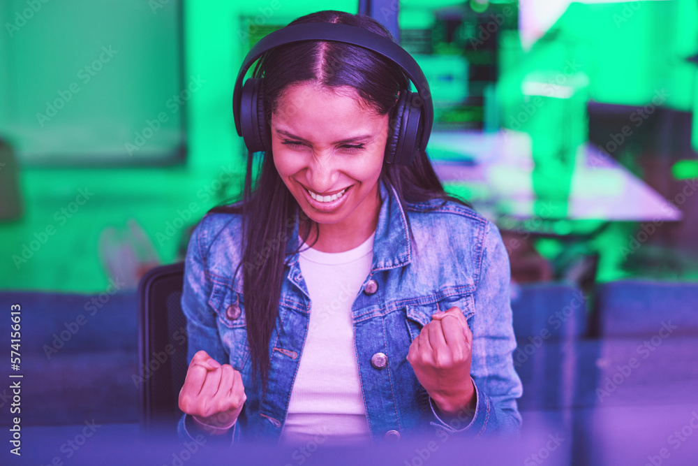 Leinwandbilder Headphones, success and celebration of hacker on computer after hacking software database. Night winner, neon light and happy woman, programmer and coder streaming music while celebrating winning.