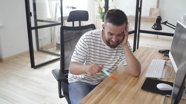 Tired male worker playing with push pop fidget toy in the office