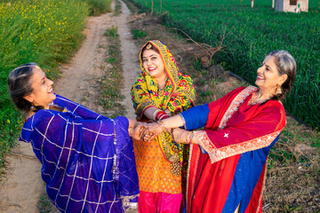 Happy indian Punjabi women dancing together in agriculture field celebrating Baisakhi or vaisakhi festival. People of punjab, Culture of india. 