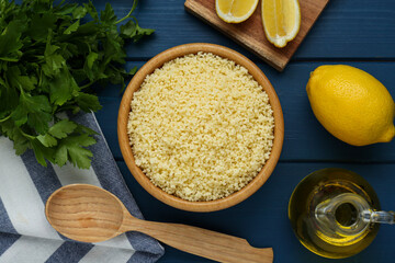 Tasty couscous and ingredients on blue wooden table, flat lay