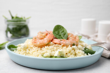 Delicious couscous with shrimps and spinach served on white table, closeup