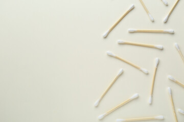 Many wooden cotton buds on beige background, flat lay. Space for text