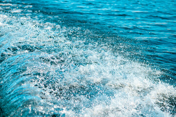 Waves on the sandy beach. Water background, blue sea water. Beautiful texture of sun glare on the...