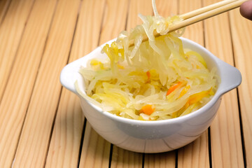Saute grated young papaya in a white bowl on a wooden table. Traditional dishes from Indonesia