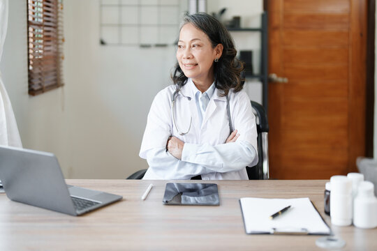 Portrait of a female doctor using a computer and a document analyzing a patient's condition before treating.