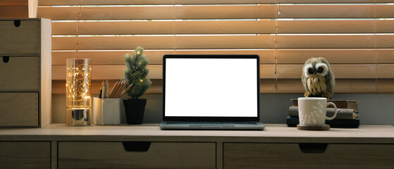 Front view laptop computer with white display on wooden counter near blinds window