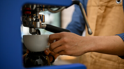 A male barista making coffee with coffee espresso machine, preparing customer's order