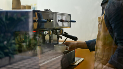 Male barista or bartender in the coffee shop making cappuccino with espresso machine