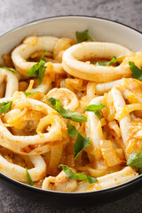 Spanish cuisine stewed calamari with onions in white wine close-up in a bowl on the table. Vertical