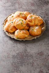 Tasty Garlic knots buns with Parmesan cheese and dried greens closeup on the plate on the table....