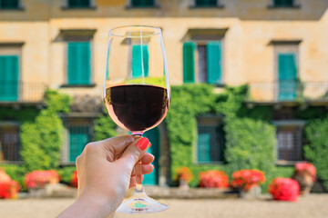 Woman s hand holding a glass of red Chianti wine at a vineyard in Tuscany, Italy