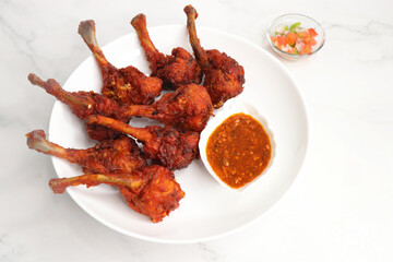 Chicken lollipop is an Indian style of Chinese appetizer. surved with schezwan chutney. Over white...