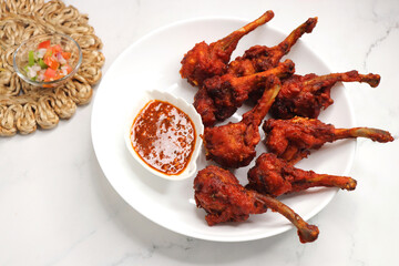 Chicken lollipop is an Indian style of Chinese appetizer. surved with schezwan chutney. Over white background. copy space. deep fried Chicken drumsticks. crispy chicken starter. 