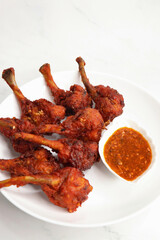 Chicken lollipop is an Indian style of Chinese appetizer. surved with schezwan chutney. Over white background. copy space. deep fried Chicken drumsticks. crispy chicken starter. 