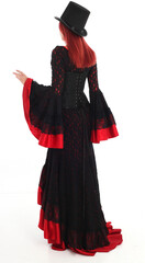 portrait of beautiful red haired woman wearing long black fantasy vampire costume gown, isolated pose on  studio background.