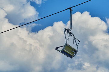 Ski lift chair hanging on a cable against a cloudy sky