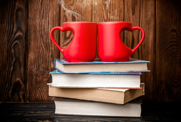 two heart shaped mugs is on a stack of books
