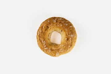 Obraz na płótnie Canvas crispy bagel strewn with sugar grains close-up, top view / highlighted / on white background