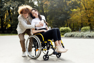 Handsome, smiling, curly-haired man in glasses hugs his girlfriend. A beautiful girl sits in a...