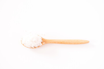 Flower of salt, is a salt that forms as a thin, delicate crust on the surface of seawater in the wooden spoon isolated on white wooden background. Called Fleur de sel in French.