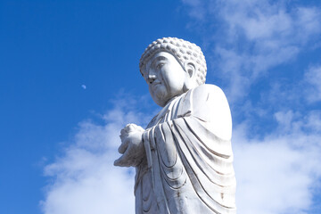 Fototapeta premium white statue of Buddha in old town in Jiamusi, city of china, visible moon in background blue sky. 