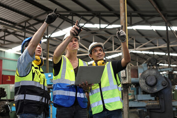 Architect men and worker checking and pointing at heavy industry manufacturing factory with computer. Multiethnic business manager looking in future with warehouse factory building