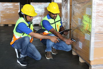 Group of warehouse workers with hardhats and reflective jackets scanning barcode on large box package for delivery to production stock and inventory in retail warehouse logistics, distribution center