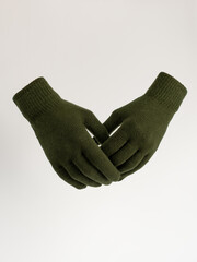 Gloves on an invisible mannequin. Khaki gloves on a light gray background studio shot. Women's knitted gloves, isolated.