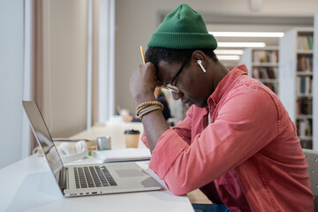 Frustration in distance education. Frustrated young African American guy sitting in front of laptop...