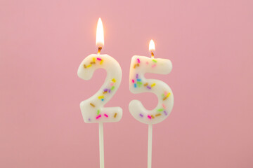 Burning white birthday candles  on pink background, number 25