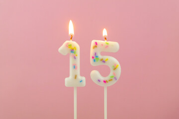 Burning white birthday candles  on pink background, number 15