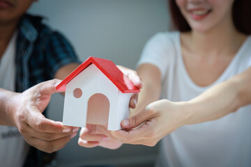 Couple holding a model house to their new house, new apartment after buying real estate.
