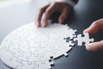 Hand putting piece of jigsaw puzzle. Team business success partnership or teamwork.