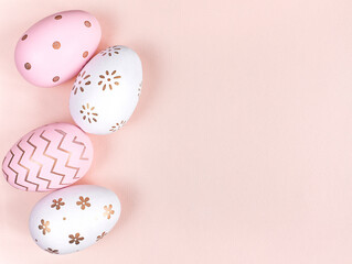 white and pink Easter eggs with a pattern on a pink background. View from above