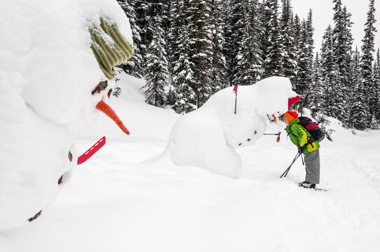 a young girl cross country skiing past snowmen in Yoho National Park near Field, British Columbia, Canada.