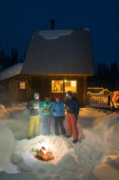 A group of adults enjoying an evening fire outside of a backcountry ski hut near Molas Pass, Silverton, Colorado.