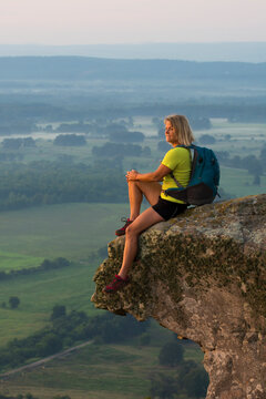 Woman sitting on sandstone overhang watching sunrise from summit&Acirc;&nbsp;of&Acirc;&nbsp;Petit&Acirc;&nbsp;Jean Mountain&Acirc;&nbsp;above Arkansas River Valley&Acirc;&nbsp;