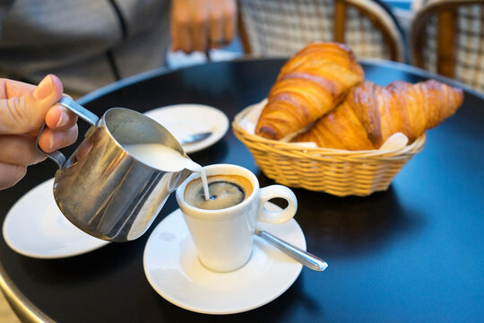 Person pouring milk into cup of espresso