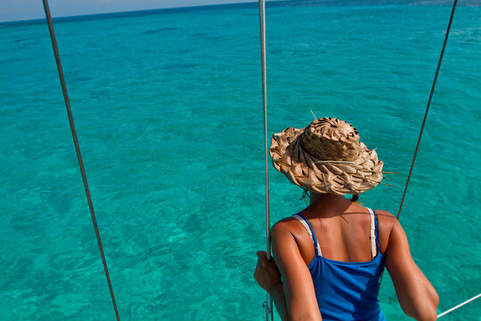 Woman preparing sailboat for anchor, sorting lines and sails, near Glovers Reef, Southwest Cayes, Belize
