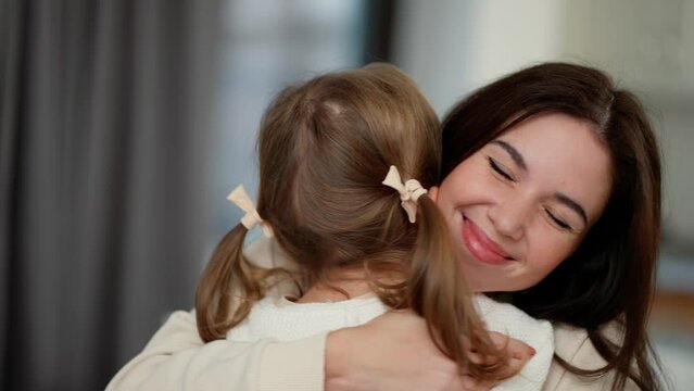 Lovely mother hugging little daughter, adorable small child daughter embrace mum