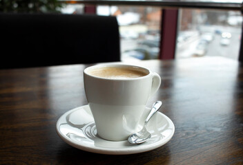 Close up white cup of coffee latte on wood table in cafe