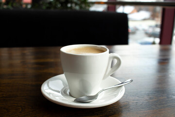 Close up white cup of coffee latte on wood table in cafe