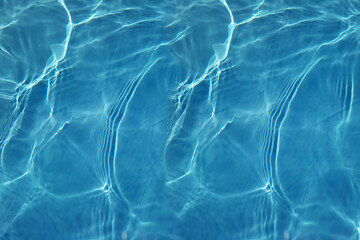 Defocus blurred transparent blue colored clear calm water surface texture with splashes and bubbles. Trendy abstract nature background. Water waves in sunlight with copy space. Blue watercolor shining