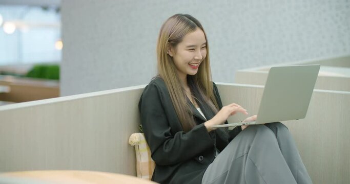 Candid Young beautiful asian business woman using laptop surfing on internet during leisure time. Happy smiling girl looking at computer shopping online, watching video movie at coworking space office