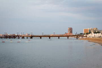 Landscape, a very early morning, empty seashore that seamlessly crosses the pier going into the sea