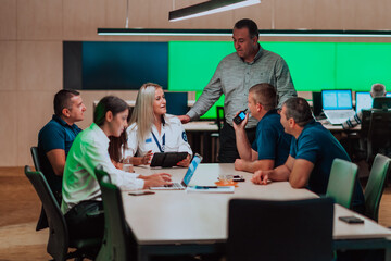 Group of security guards sitting and having briefing In the system control room They're working in security data center surrounded by multiple Screens