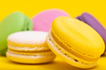 Traditional french multicolored macaroons falling on yellow  background